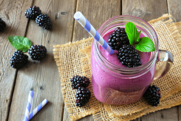 Wall Mural - healthy blackberry smoothie in a mason jar glass. close up, downward view table scene against a rust