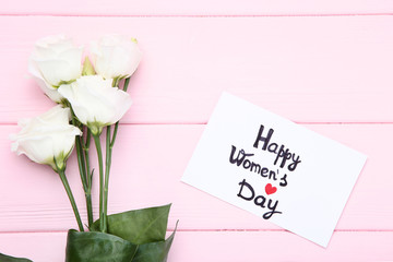  Text Happy Women's Day with eustoma flowers on pink wooden table