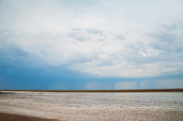 Beautiful natural textural background on a salt lake, river. Salt lake Elton, Russia, before rain and thunder, sunset on the water, solitude, silence, calm