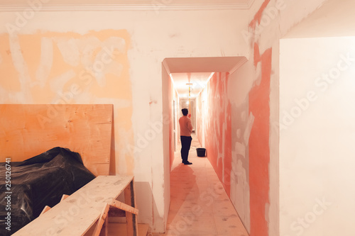 Worker Is Painting The Ceiling By Paint Roller In Corridor An