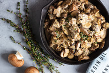 Meat Stewed With Mushroom And Thyme In A Cast-iron Pan.  Grey Concrete Background. Copy Space. 