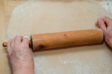 Sticker - Rolling pasta dough. The woman uses a rolling pin to prepare the homemade pasta. The concept of cooking and preparing homemade food.