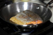 © Peter Kim - Wild caught Coho salmon frying in a pan with the skin side up.