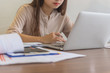 © Quang - Businesswoman holding pen and using laptop in the office