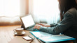 © Lek - Asian business woman using computer for working in office with coffee and smartphone on wooden table