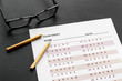 © 9dreamstudio - Take the exam. Exam sheet near glasses and pencil on black background