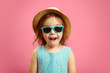 © Ilshat - Portrait of surprised girl with open moutn, wears in panama hat and sunglasses, expresses surprise and delight, stands over pink isolated background.