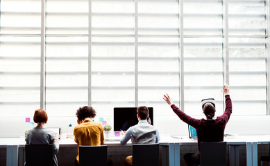 Wall Mural - A rear view of group of young businesspeople with VR goggles working in office.