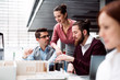 © Halfpoint - Group of young architects with model of a house working in office, talking.