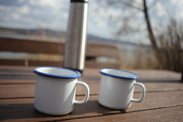 Two cups and a thermos on a wooden table