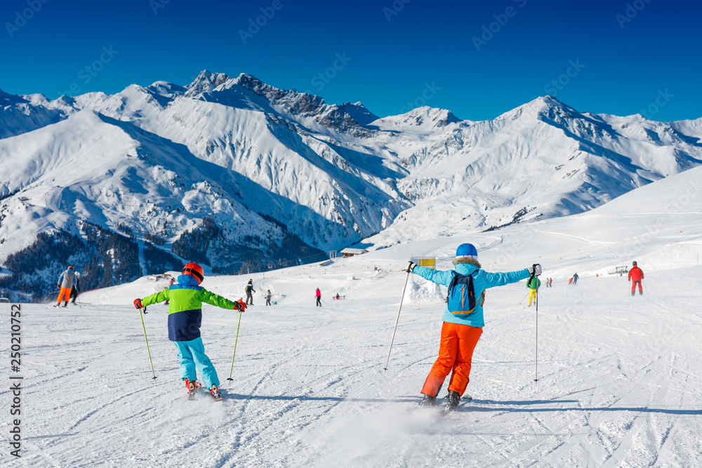 Cute skier boy with his mother having fun in a winter ski resort. - obrazy, fototapety, plakaty 