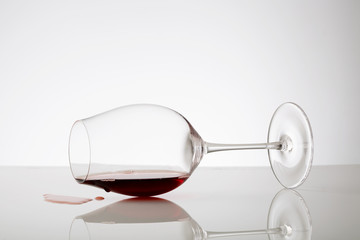 Spilled red wine out of glass on white background