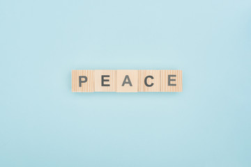 top view of peace lettering made of wooden cubes on blue background