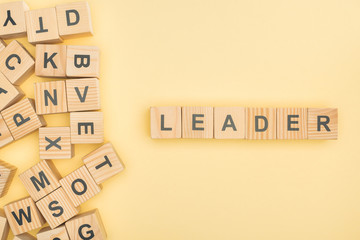 Wall Mural - top view of leader lettering with wooden cubes on yellow background