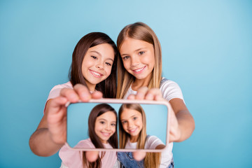 Canvas Print - Close up photo two little she her blond brunette girls long pretty hair telephone make take selfies talk tell speak millennials wearing casual jeans denim t-shirts isolated blue bright background