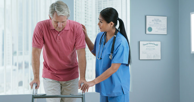 Wall Mural -  - Physical therapist or doctor helping older male patient learn to walk with a walker. Female nurse assisting senior man with recovery after surgery