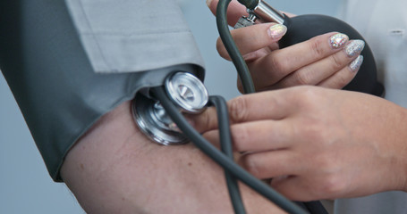 Wall Mural - Extreme close up on stethoscope and blood pressure cuff on arm as doctor checks older male patient. Rack focus to pumping bulb to inflate sphygmomanometer