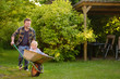 © Maria Sbytova - Happy little boy having fun in a wheelbarrow pushing by dad in domestic garden on warm sunny day.