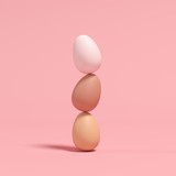 Stacked eggs on pink background. Minimal Easter concept idea.