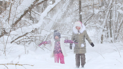 Wall Mural - Two little girls playing with snow in winter forest. Throwing the snow in the air