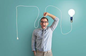 Wall Mural - Young man smiles and holds a bright light bulb on the wire