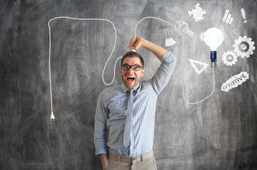 Wall Mural - Young man smiles and holds a bright light bulb on the wire