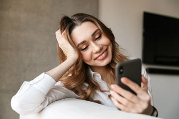 Poster - Beautiful young business woman dressed in formal clothes shirt indoors using mobile phone.