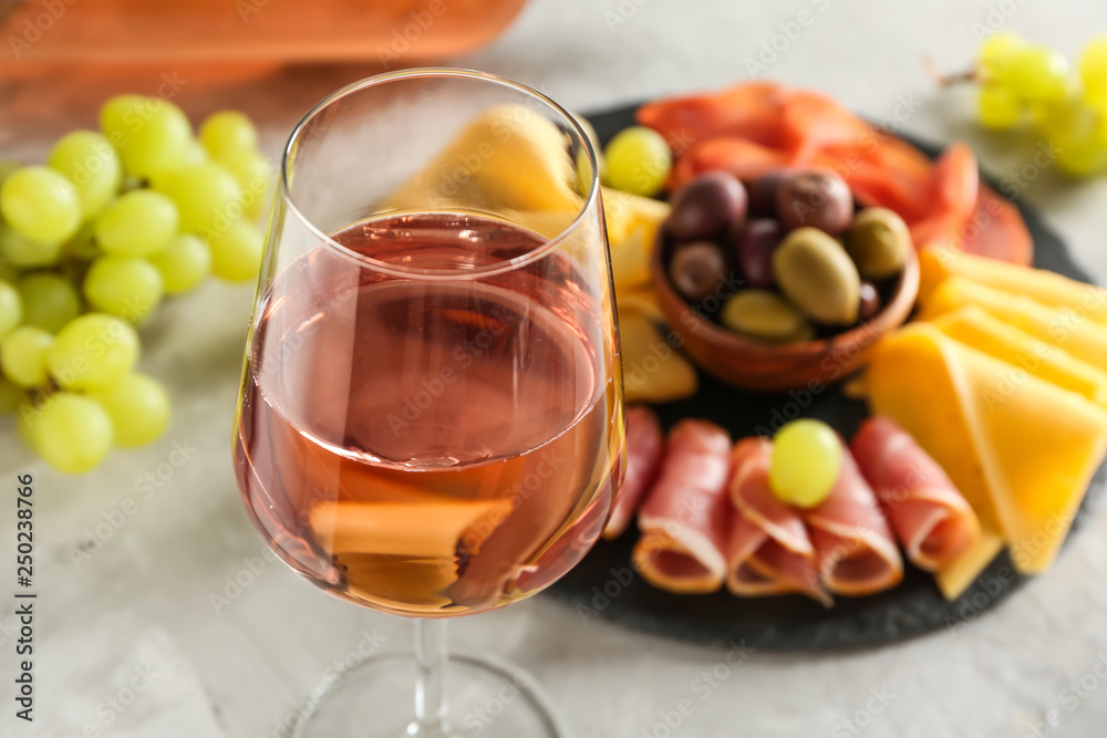 Glass of tasty wine with snacks on grey table