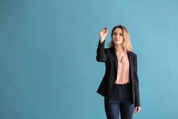 Woman in formal clothes writing something on virtual screen against color background