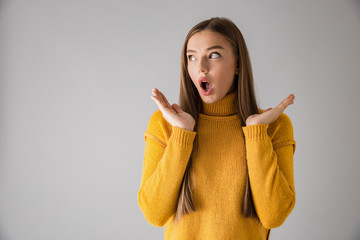 Wall Mural - Shocked excited young woman isolated over grey wall background.