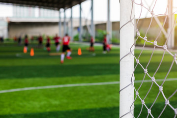 Wall Mural - White goalposts and mesh of goal with blurry football players