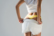 Cropped view of woman in yellow panties taking off shorts on grey background