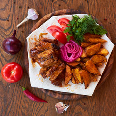 Wall Mural -  Grilled pork ribs with pickled onions, fresh tomatoes and greens on a wooden surface. near onion, garlic, pepperoni, tomato, cutlery, olive oil in a glass bottle. B-B-Q