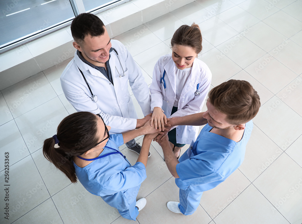 Team of doctors putting hands together in clinic