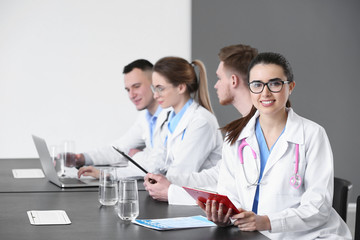 Wall Mural - Young doctors sitting at table during meeting in clinic