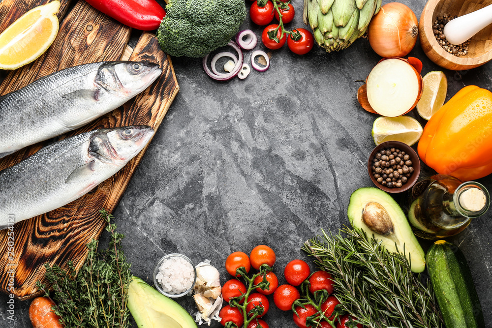 Frame made of raw seabass fish and products on grey background