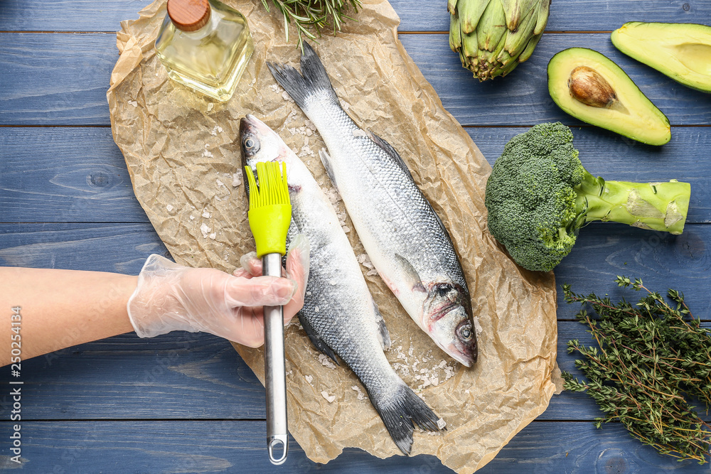 Woman preparing tasty seabass fish on table