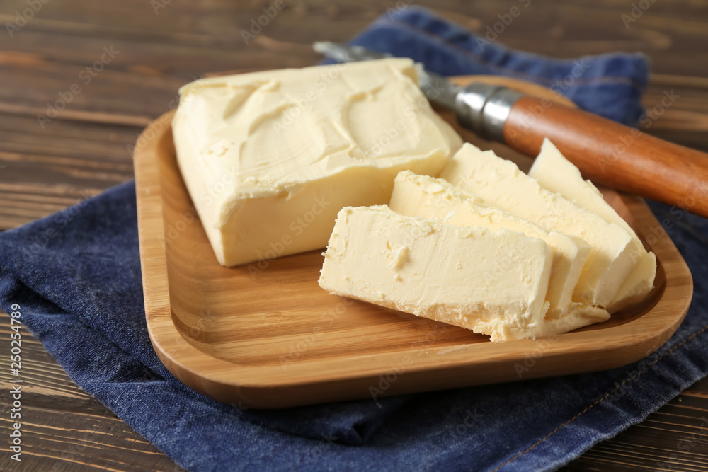 Plate with butter on wooden background