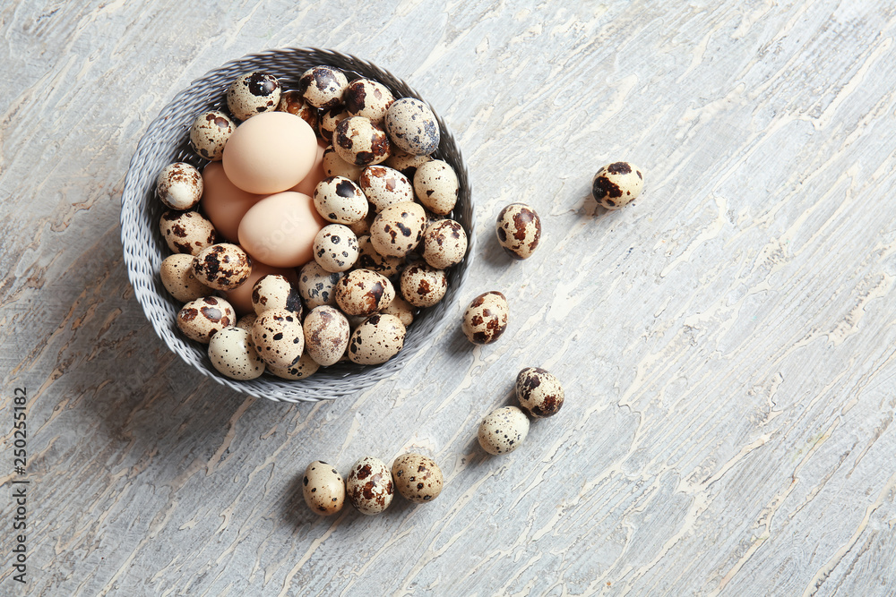 Bowl with fresh quail and chicken eggs on table