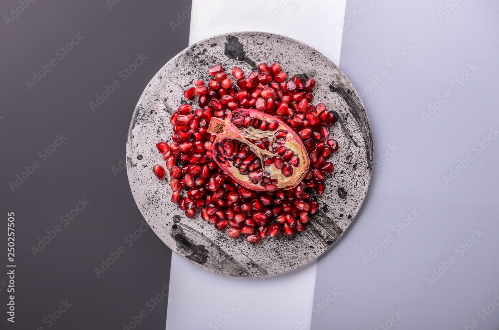 Plate with piece of ripe pomegranate and seeds on table