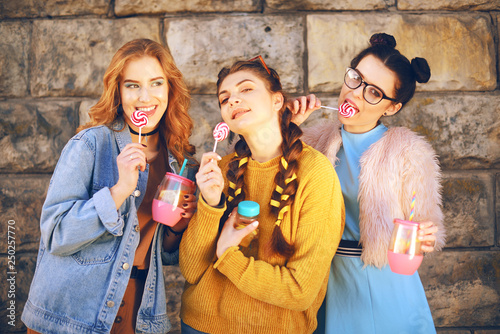 Three Beautiful Girls Eat Lollipops And Drink Lemonad In Pink