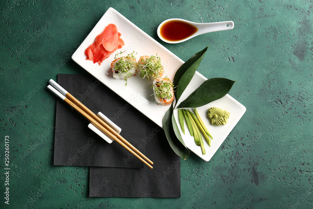 Composition with tasty sushi rolls on color background