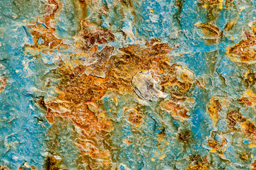 close-up of an old and damaged ship hull, partly still covered with light blue paint, partly eaten away by rust