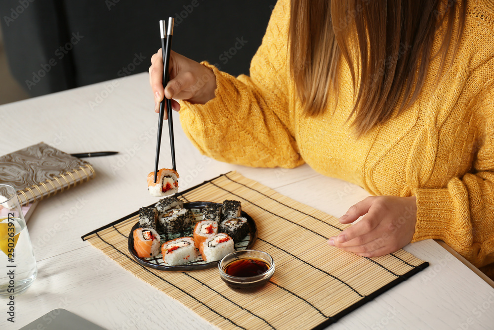 Woman eating tasty sushi rolls at home