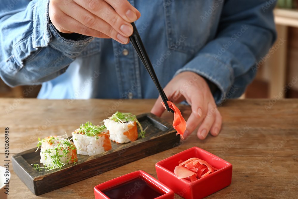 Woman eating tasty sushi rolls in cafe