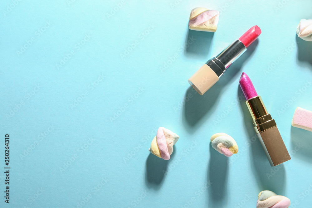 Lipsticks and sweet marshmallow on color background