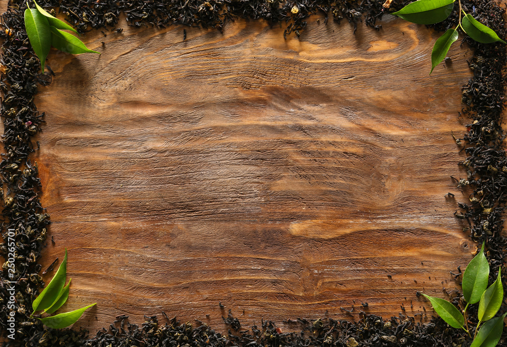 Frame made of dry tea leaves on wooden background