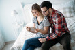 © NDABCREATIVITY - Young happy couple using tablet in bedroom