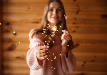 Canvas Print - Beautiful woman with sparkler on wooden background