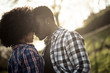 © simona - Love and relationship concept with african american couple outdoor - hipster casual shirts and face to face close people - green warm filter and nature in background with sunlight